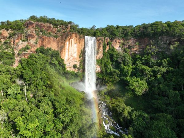 Imagem de Cachoeira com vegetação no entorno e um arco-íris.